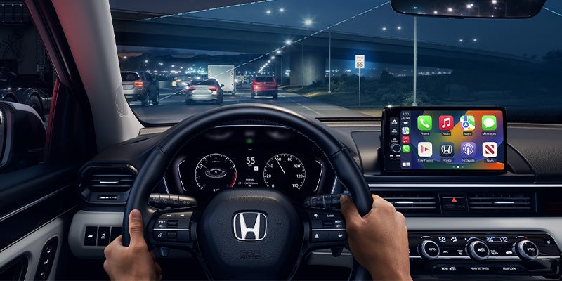Driver’s view of Honda SUV interior at night showing steering wheel and infotainment screen with navigation.