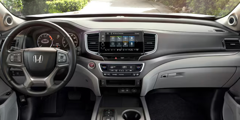 Honda Ridgeline interior showing front seats, steering wheel, and center console in black and red trim.
