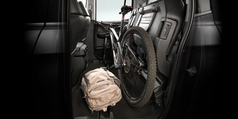 Interior of pickup truck with bicycle secured in cargo area next to a backpack.
