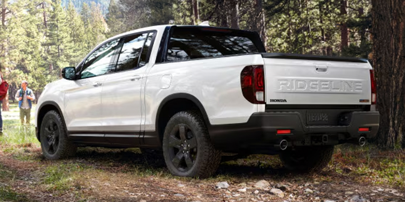 Rear view of Honda Ridgeline pickup truck parked on forest trail.