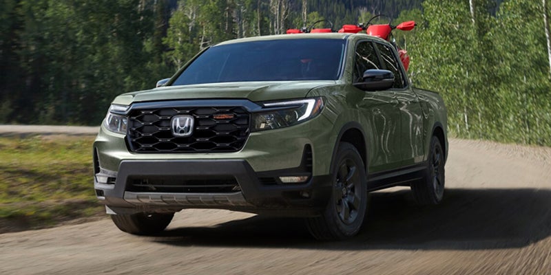 Front view of Honda Ridgeline TrailSport driving on forest road in green paint.